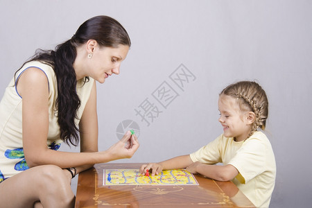 母亲和女儿坐在桌边玩棋局游戏图片