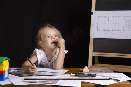 建筑师形象中的四岁女孩坐在桌边的有图画女孩背景是董事会的图画图片