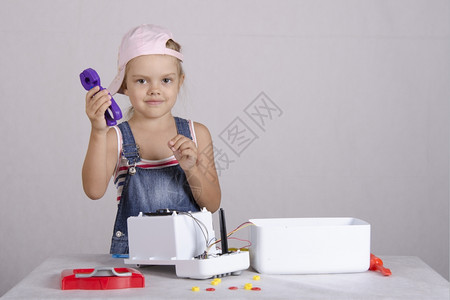 钉机螺丝钉女孩在修理机和玩具微波炉中耍女孩拿着一对钳子看框架背景
