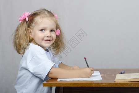 女孩坐在桌子上用笔记本写手柄分心往右看图片
