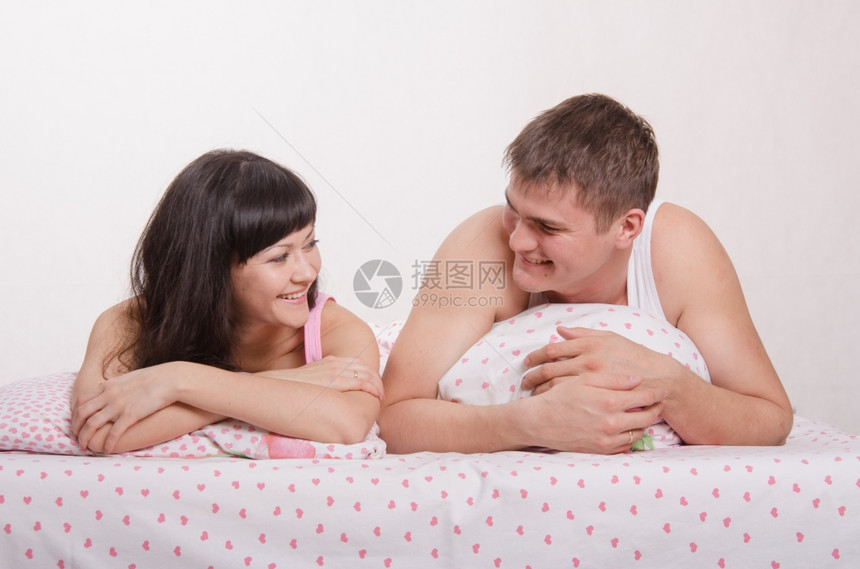年轻美丽的女孩和男人亲吻抱在床上图片