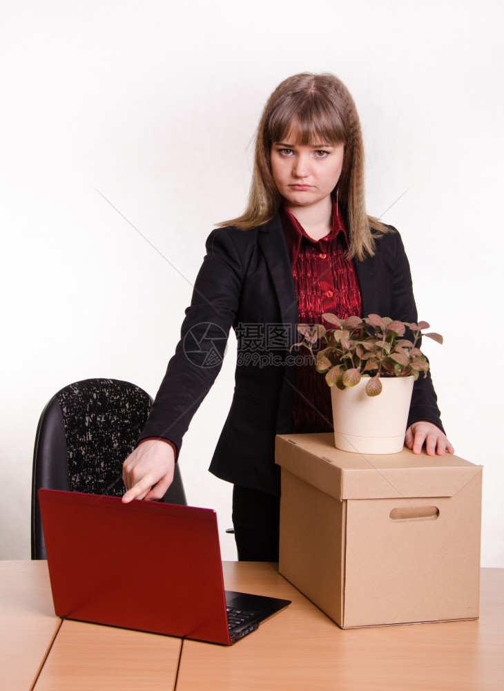 妇女从办公室工作被开除悲哀地看着框架关上笔记本电脑站在装东西和花房的盒子旁边图片