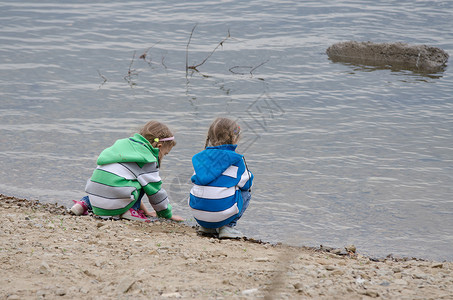 两个女孩蹲在河边玩水图片