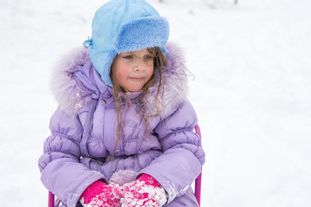坐在雪橇上着的疲累女孩坐着雪橇的5岁女孩坐着累和无礼的步行起来图片