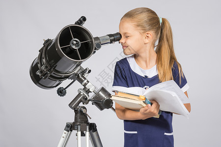女学生透过望远镜看书本图片