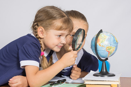 两个女孩友透过放大镜看地球图片