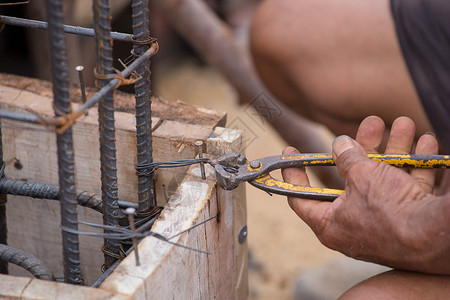工人背着电线在建筑工地修炼钢管时与铁钉一起工作的建筑人近身手设计图片