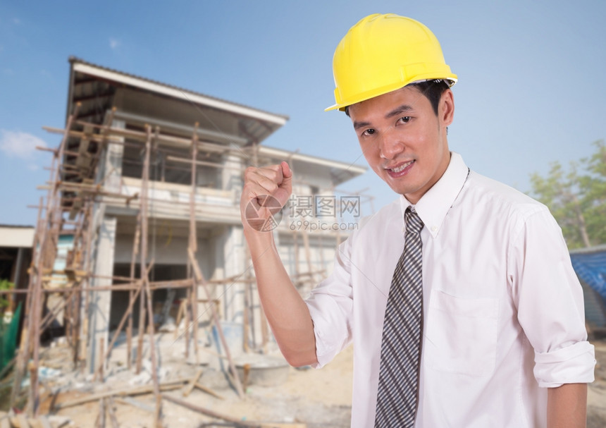 快乐的工程师以举臂庆祝成功的概念房屋建设背景图片