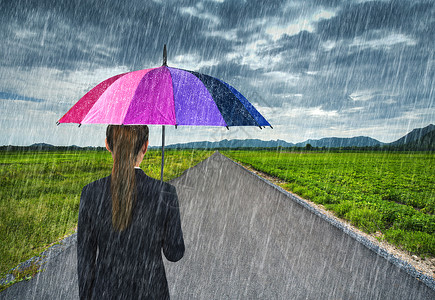 在乡间小路上一位手持五颜六色雨伞的女商人背景图片