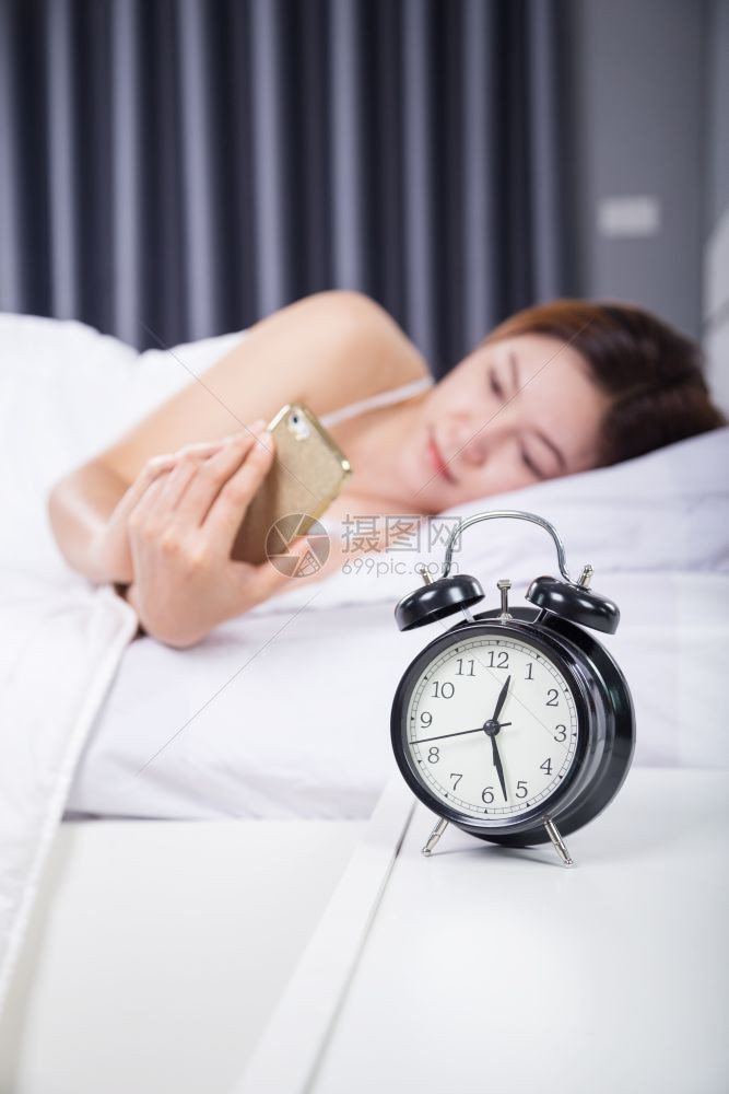 女人在卧室的床上用智能手机图片
