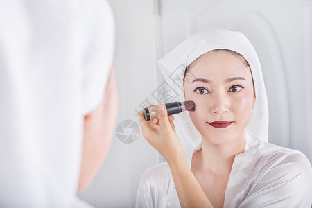 妇女看着镜子用刷化妆图片