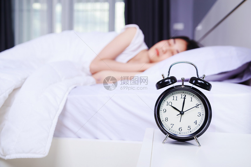 桌子上的闹钟和睡在卧室床上的女人图片