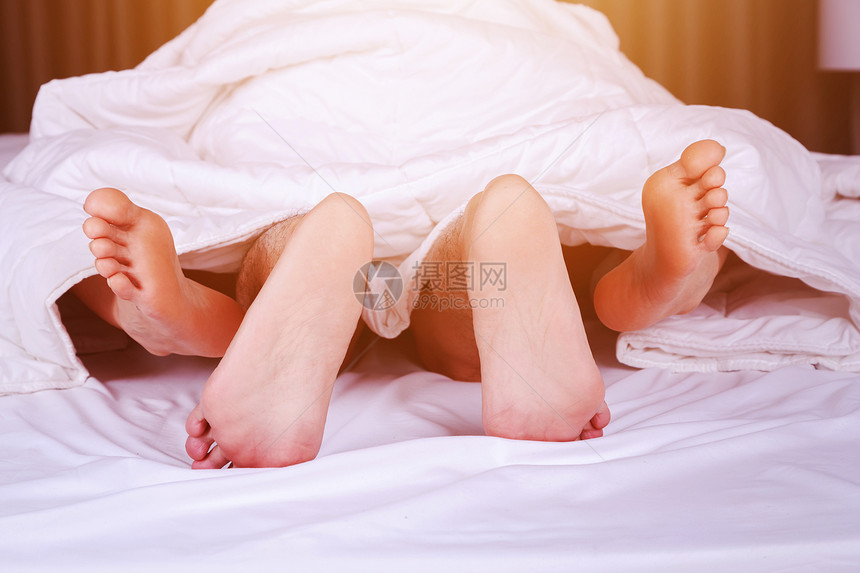 从床上的毛毯下看到一对夫妇的双脚图片