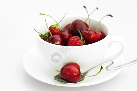 白纸上隔离的茶碟勺樱桃和草莓图片