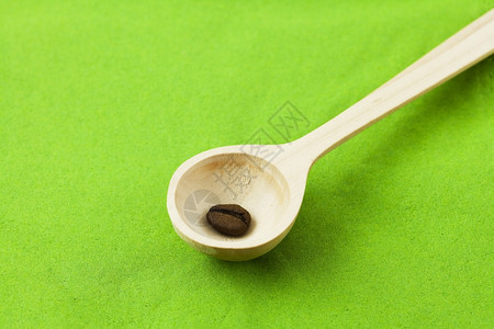 绿色背景的木勺子中咖啡豆背景图片