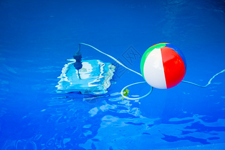 红色的玩具球在游泳池里漂浮着多彩的海滩球紧挨着他水下一个清洁机器人背景