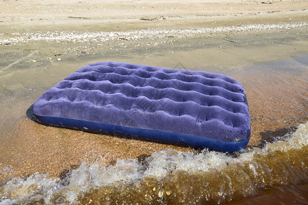 在池塘中游泳的蓝色充气床垫在海滩上游泳的蓝色充气床垫图片