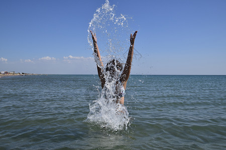 她喷洒在海水中黑发女孩和洗澡享受海的滋味背景图片