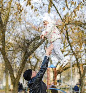 喜悦的父亲把他女儿扔了起来秋天在公园里走图片