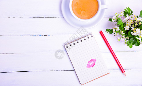 纸笔记上面有红口吻的痕迹下一杯黑咖啡左边空背景图片