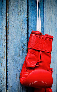 红色拳击手套挂在木蓝色表面关闭图片