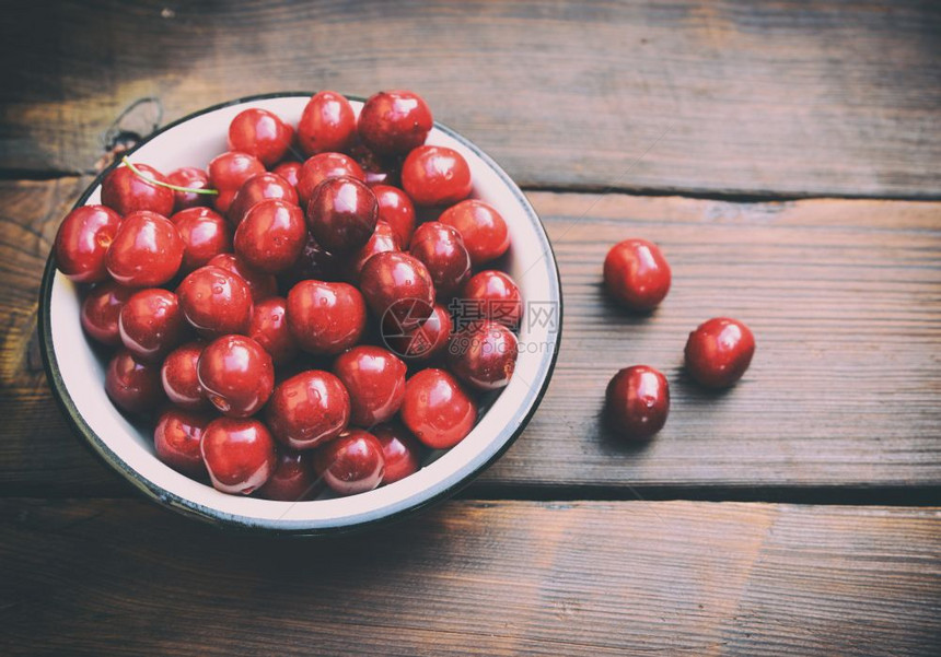 成熟的红樱桃放在棕色桌子上的铁盘子里复古色调图片