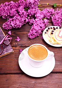 咖啡在白杯里配着一个碟子在束盛的花后面图片