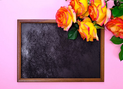 粉红色背景上的空黑边框和黄色玫瑰花束图片