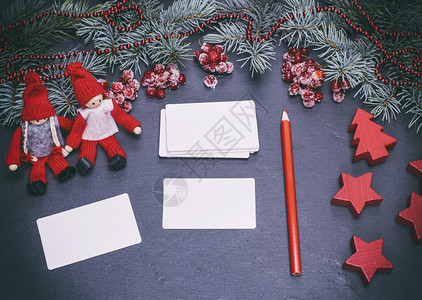 黑色背景的白纸名片和圣诞装饰品中的红铅笔图片