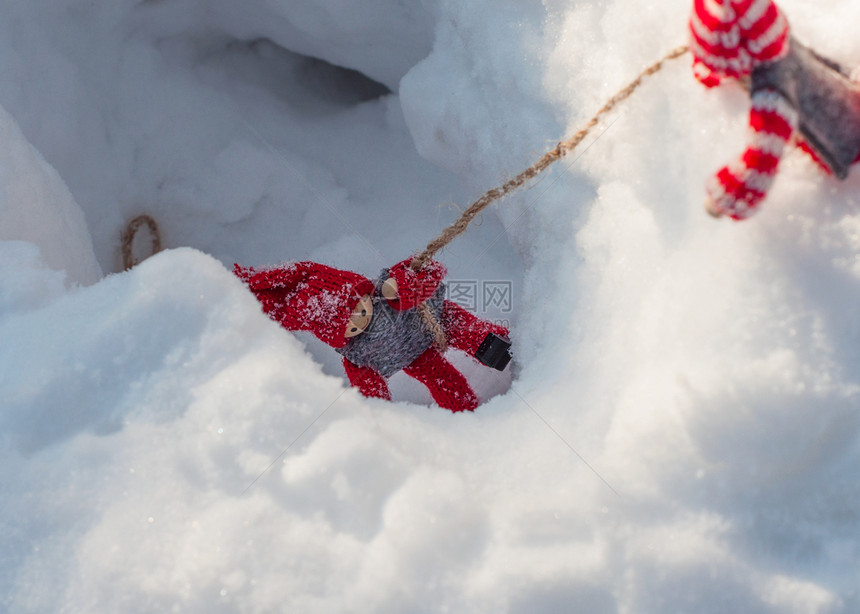 小木玩具在营救现场和帮助洋娃拉绳从雪沟另一洋娃图片