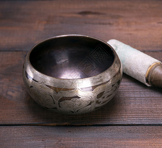 一个空的铜唱碗和棕色桌子上的木棍关门图片