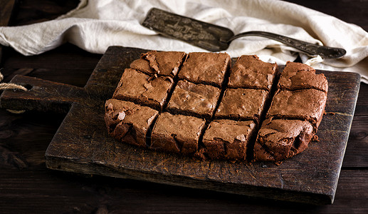 褐色厨房切面板上方形成烤面巧克力蛋糕饼切成方形黑暗的高清图片素材