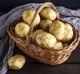 小土豆在棕色的篮子里在木制桌边的小马铃薯在棕色的篮子里小土豆图片