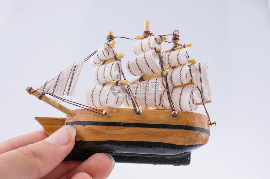 在白色背景上手头的小木模型船图片