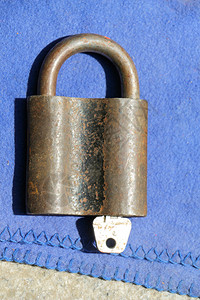 旧生锈的金属锁里面有一把钥匙蓝色布图片
