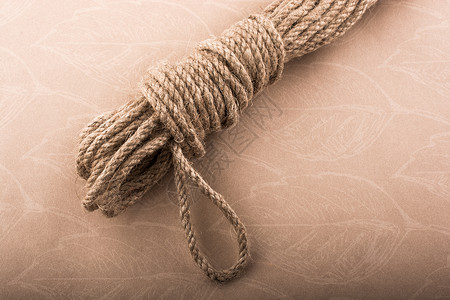 身穿褐色背景的麻布绳捆绑高清图片