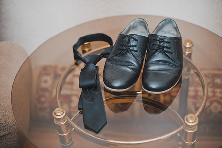 男人的装饰品放在玻璃桌上有靴子和领带图片