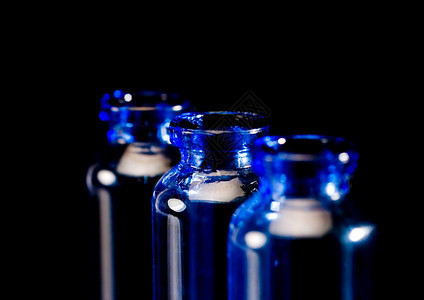 黑色背景反光的蓝玻璃瓶图片