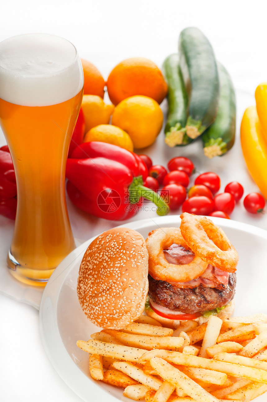 美国经典汉堡三明治洋葱环和薯条啤酒杯新鲜蔬菜背景图片