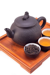 青茶泥和竹木盘上的茶壶和杯子在白色上隔绝背景图片