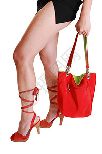 身穿短黑裙子的年轻女美丽长腿身着绿衬衣和红色高跟鞋的手提包白底带长图片