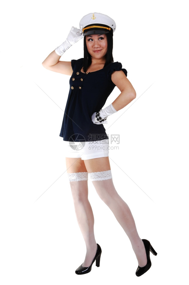 一个年轻的亚洲美女穿着水手制服白短裤长袜和手套穿着高跟鞋和水手帽站在工作室敬礼图片