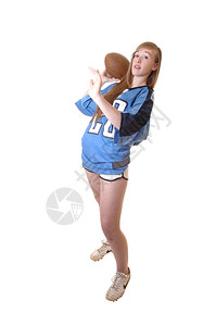 一个穿着蓝色足球服的年轻女孩站在工作室展示如何踢足球白种背景图片