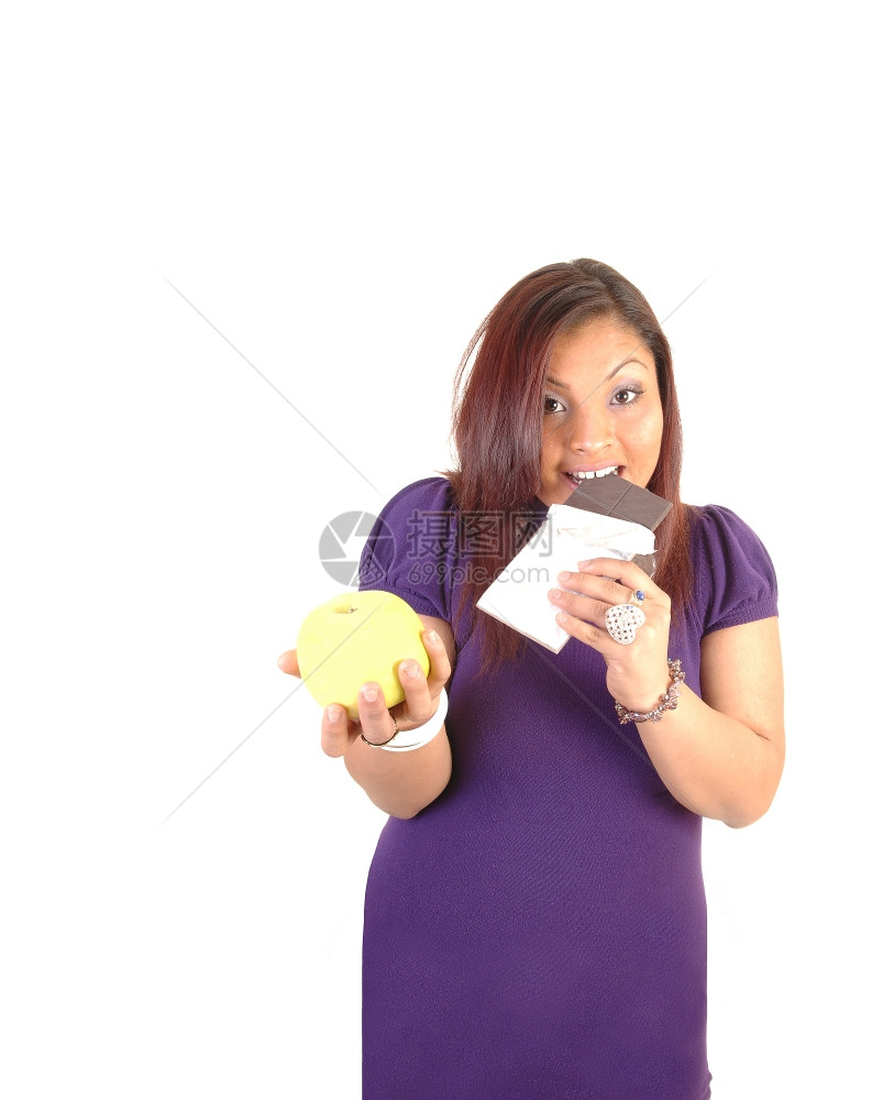 穿紫色裙子的年轻女人拿着黄苹果和巧克力更喜欢吧白底带图片