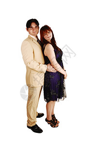 一个年轻的欧洲夫妇站在白色背景穿着米西装她穿着蓝色黑礼服图片