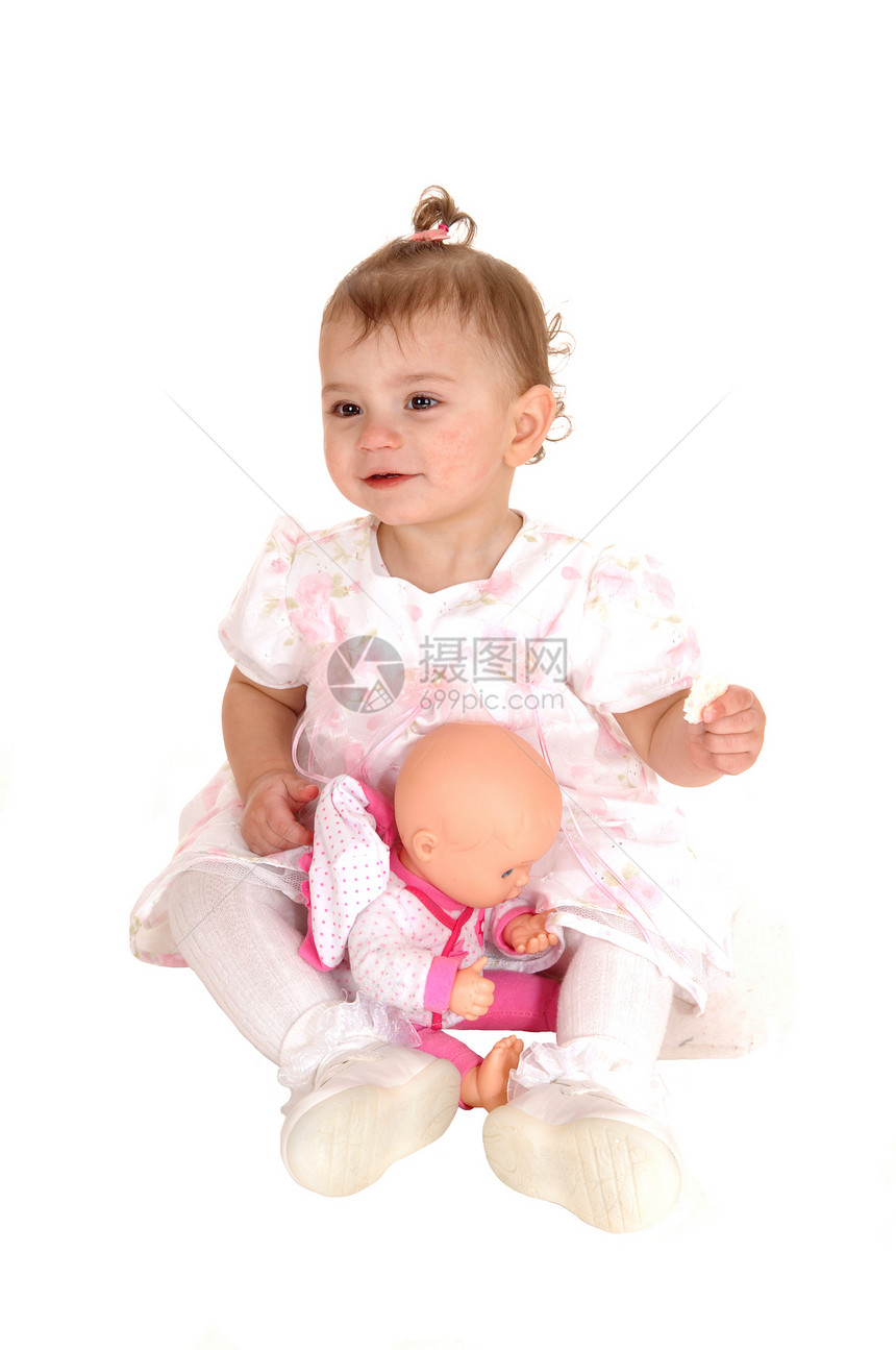 一个可爱的金发女婴坐在地板上拿着饼干玩甜圈与白种背景隔绝图片