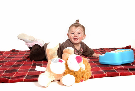 小毯子一个穿着棕色礼服的可爱女婴躺在地板上的毯子为了白色背景而孤立无援背景