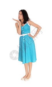 一个穿着蓝裙子的年轻美女站在白地边吹着一个吻可爱的女人吹着一个吻图片