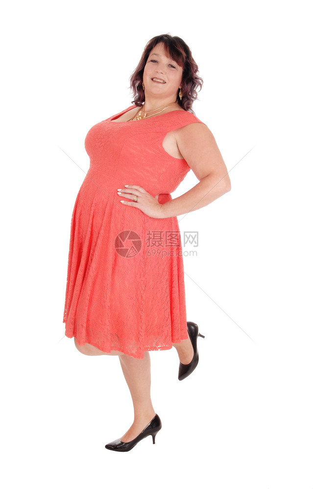 一位美丽的女士站在一条腿上穿着红裙子在四十多岁的时为白色背景而隔离图片