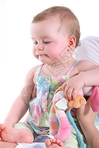 女婴被放在一个坐着的姿势上看她的脚背景图片